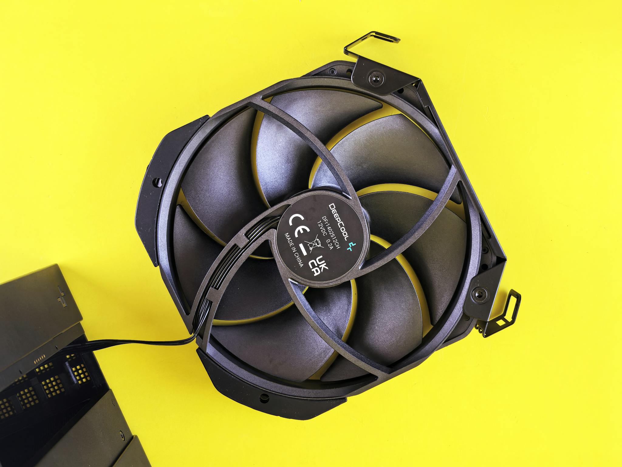 A top-down view of a computer cooling fan against a vibrant yellow background, highlighting its design.