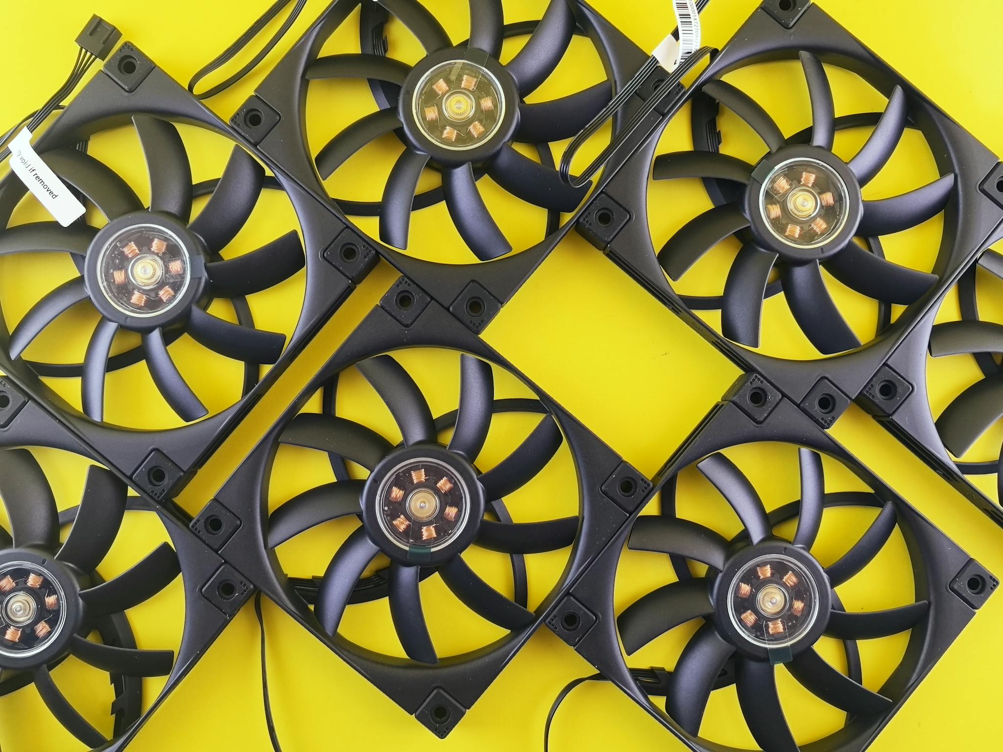 Multiple black CPU cooling fans arranged on a vibrant yellow background, showcasing tech elements.