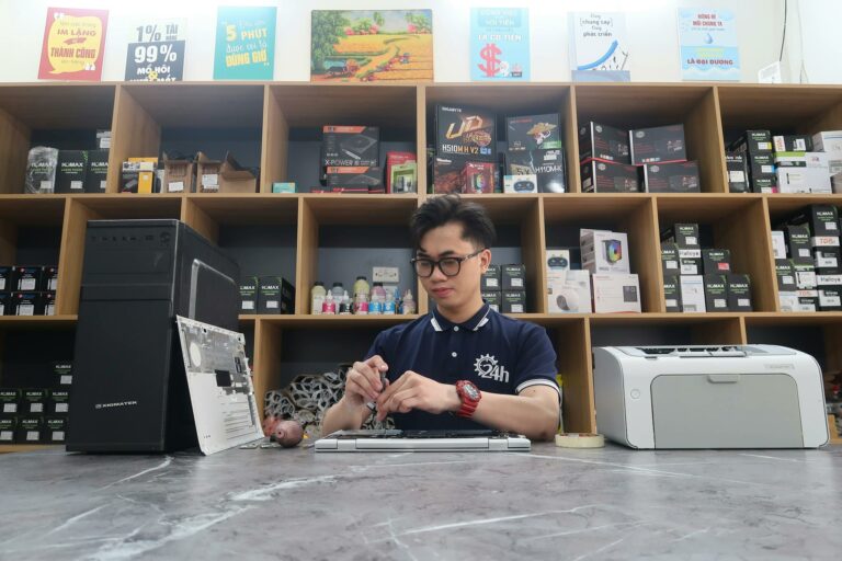 Young technician fixing a computer in a modern electronics store setting.